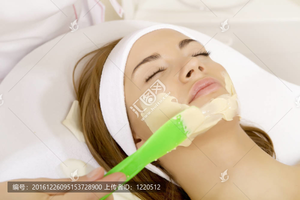 年輕女人用刷子在臉上得到美容面膜