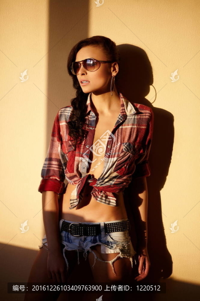 美麗時(shí)尚性感的黑人女孩穿著牛仔褲和五顏六色的襯衫在眼鏡后面的日落室內(nèi)肖像