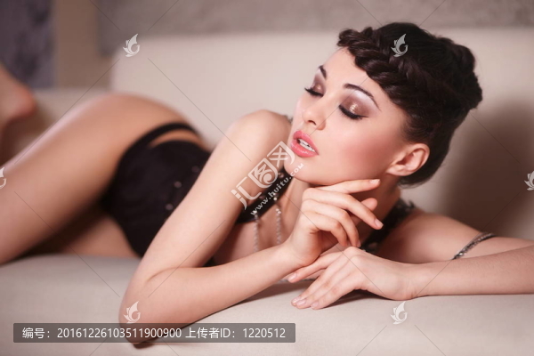 美麗性感的時尚女孩的黑色緊身衣躺在沙發(fā)上，室內(nèi)明亮的化妝和發(fā)型