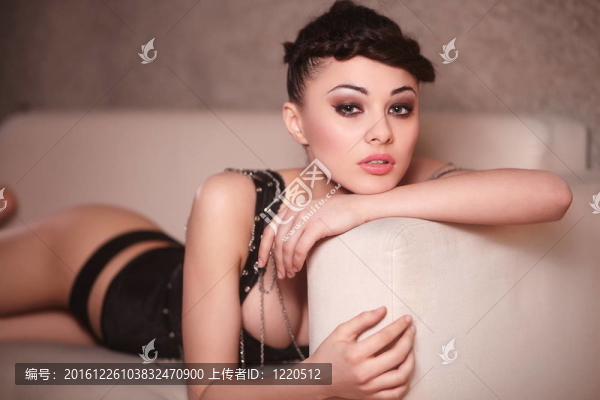 美麗性感的時尚女孩的黑色緊身衣躺在沙發(fā)上，室內(nèi)明亮的化妝和發(fā)型