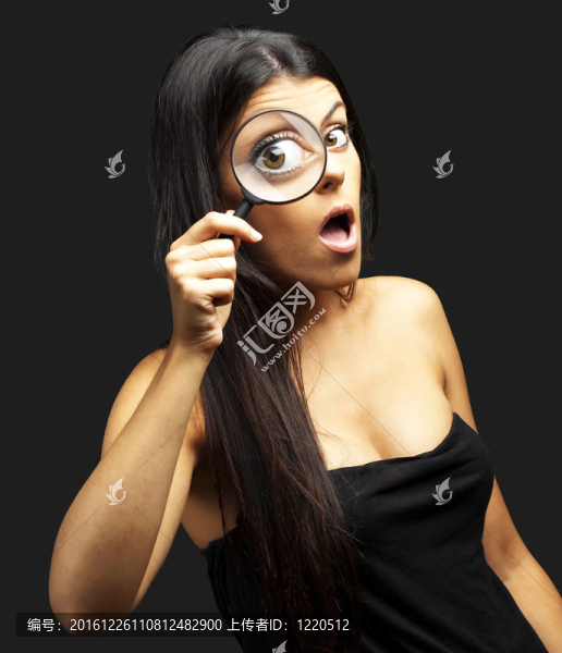 年輕婦女的肖像驚訝地通過放大鏡看黑色