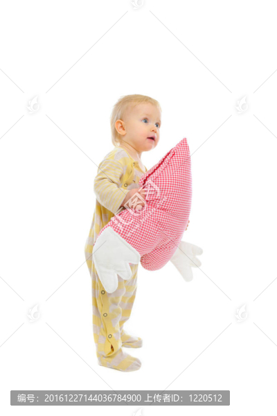感興趣的嬰兒站在心形枕和尋找角落