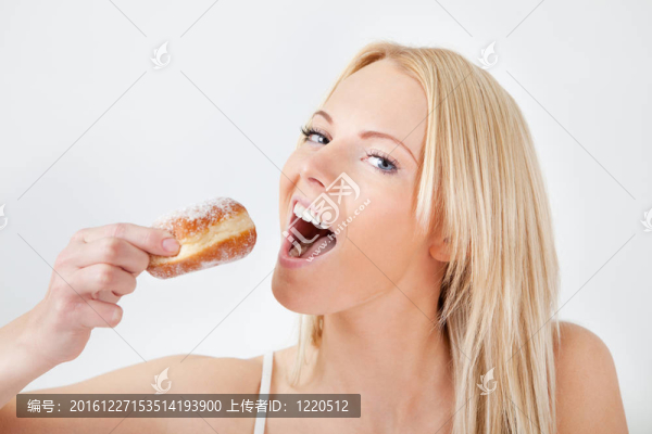 美麗的女人吃美味的甜甜圈