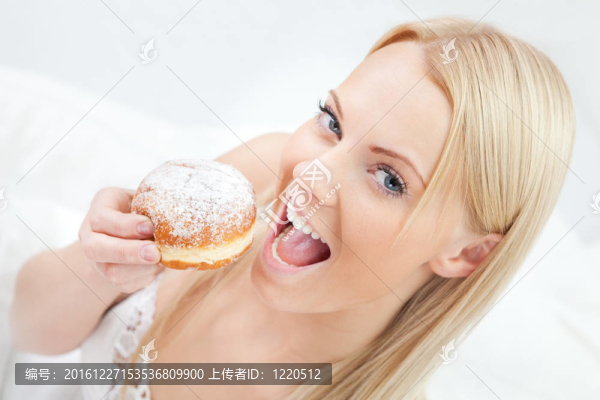 美麗的女人吃美味的甜甜圈
