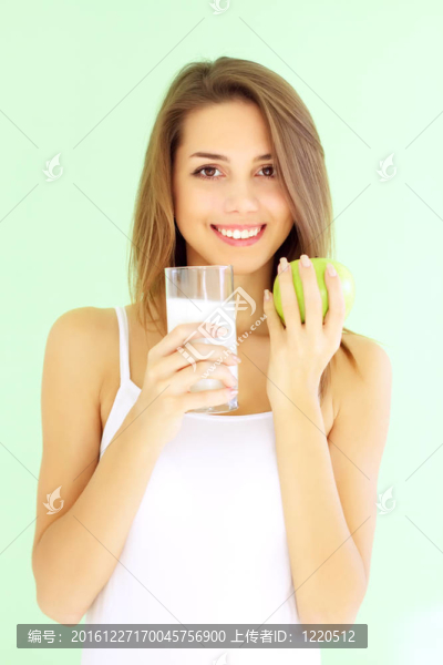 微笑的女孩拿著一杯牛奶和蘋(píng)果