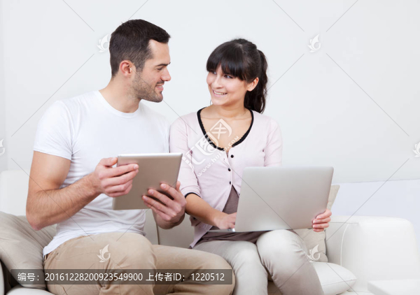 年輕夫婦在沙發(fā)上使用筆記本電腦