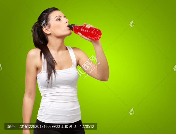 在綠色的年輕動感的女人飲用等滲飲料的肖像