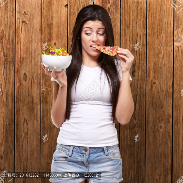 年輕婦女吃比薩餅和尋找沙拉的肖像