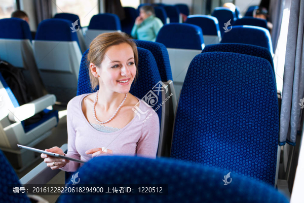 年輕女子坐火車旅行時(shí)使用平板電腦