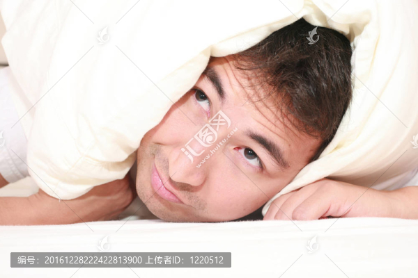男人試圖睡在頭上的枕頭和接近喚醒時間