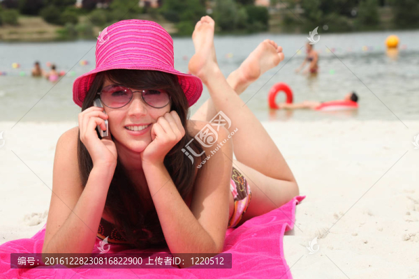 微笑著20歲的亞洲女孩在海灘上放松和打電話