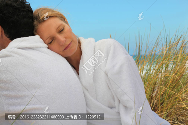 夫婦坐在浴袍在海