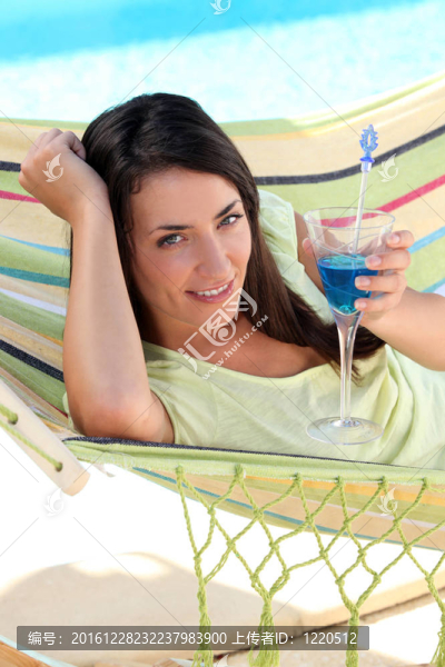 在吊床上有一個(gè)雞尾酒飲料的女人
