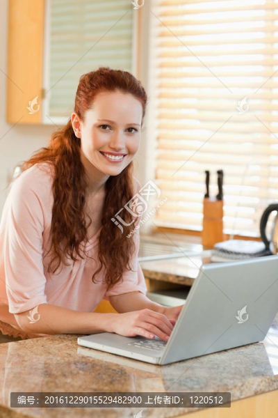 婦女與她的筆記本電腦旁邊的廚房柜臺