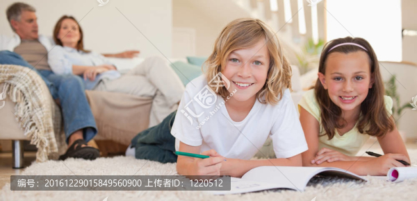 兄弟姐妹在地板上做作業(yè)，后面跟著父母