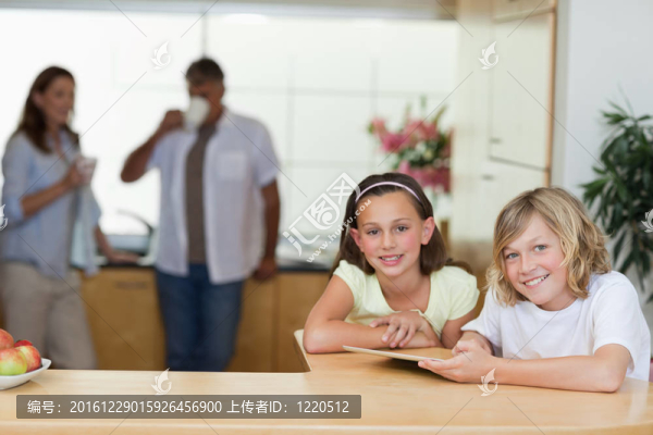 兄弟姐妹在廚房里用平板電腦和父母在一起