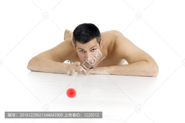光著上身的男子躺在地板上玩彈珠
