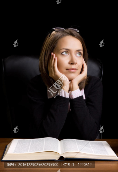 在黑色背景的書桌上有書的年輕女人