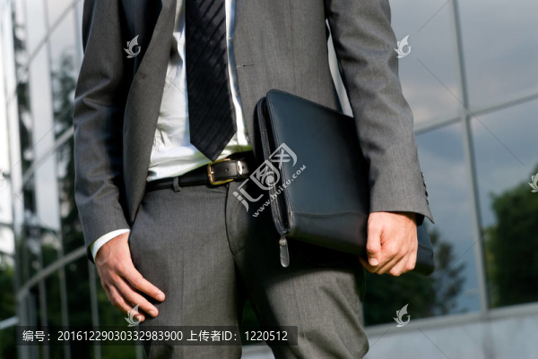 無法辨認(rèn)的商人與手提箱特寫在現(xiàn)代建筑的背景