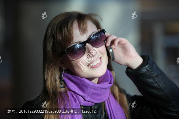 年輕漂亮的女人在太陽鏡與電話