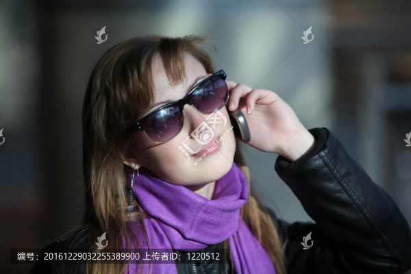 年輕漂亮的女人在太陽鏡與電話