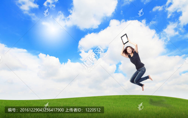 快樂女孩跳和顯示觸摸墊電腦在草地上