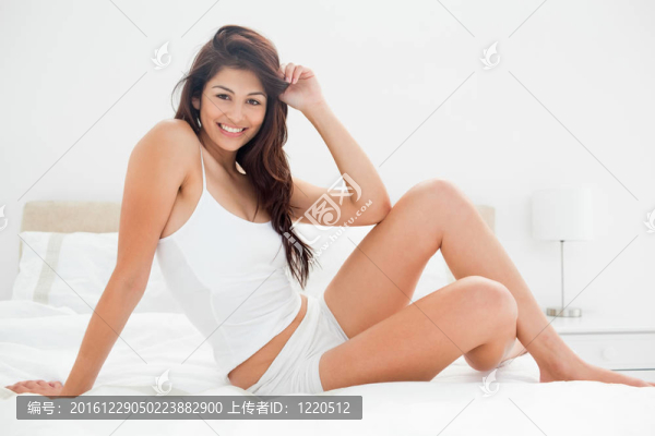 一個女人坐在床上；一只膝蓋抬起；一只胳膊在她的頭發(fā)上摩擦；另一只胳膊支撐著她。