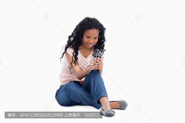 一個(gè)吃驚的女人坐在地板上，用手機(jī)發(fā)短信