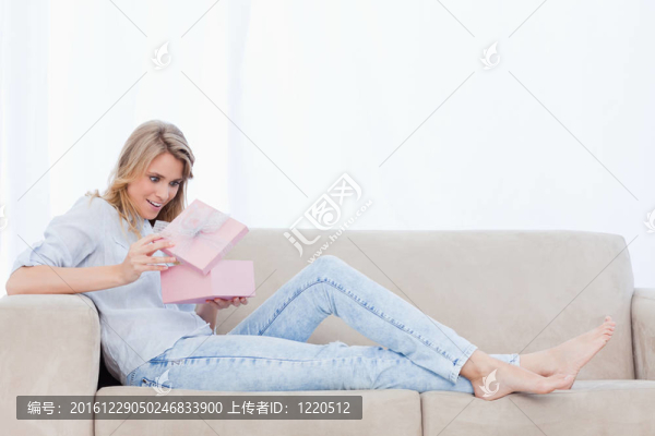一個驚訝的女人看著一個粉紅色盒子里的禮物