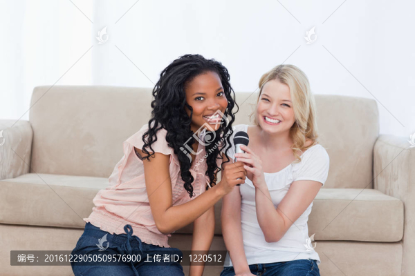 坐在地板上的兩個(gè)女人拿著麥克風(fēng)