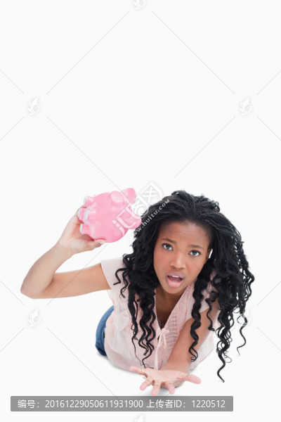 一位憂心忡忡的年輕女子抱著一只空存錢罐