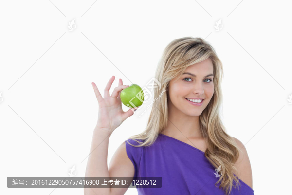 微笑的金發(fā)女人拿著一個(gè)綠色的蘋(píng)果