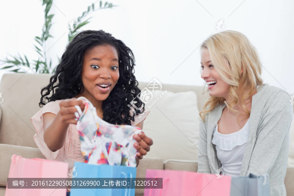 兩個笑著的女人看著她們買的衣服