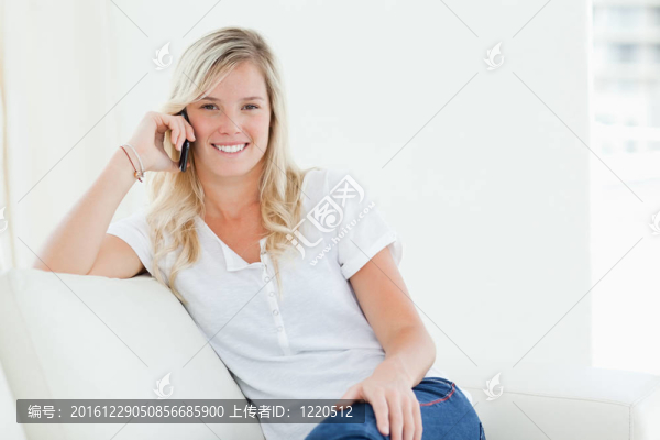 一個女人一邊微笑一邊看著電話邊說話