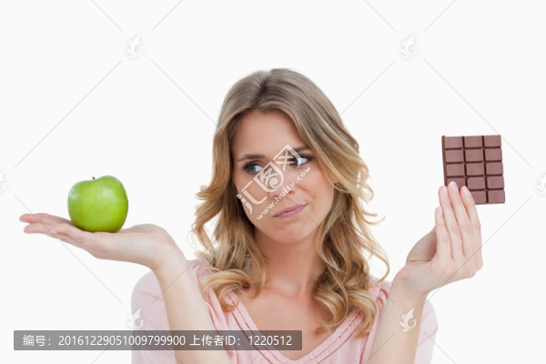 年輕的金發(fā)女子猶豫的巧克力和蘋果之間