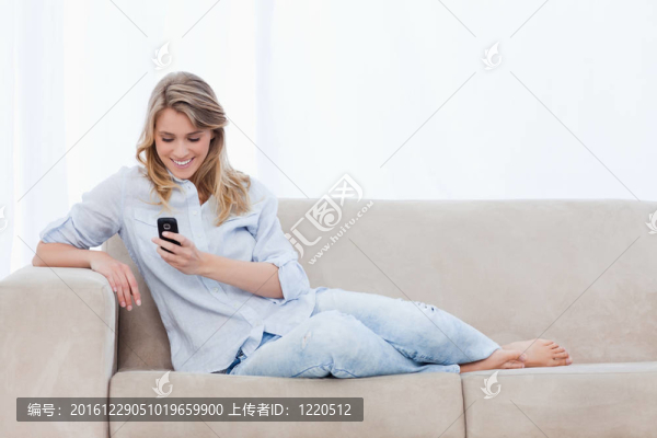 一個坐在沙發(fā)上的女人手里拿著一部手機