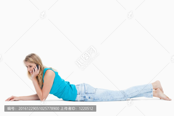 躺在地板上的一個(gè)快樂的女人正在用手機(jī)說話