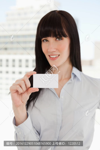 一個(gè)女人微笑著，手里拿著一張名片