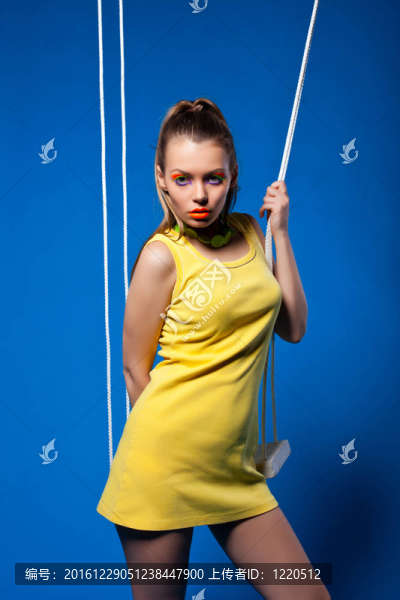 性感的女人在黃色的秋千與明亮的化妝
