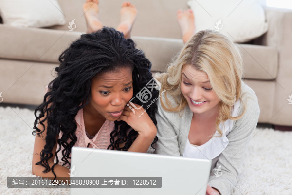 兩名婦女用筆記本電腦躺在地上