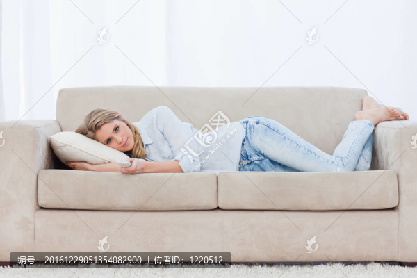一個拿著電視遙控器的女人躺在沙發(fā)上