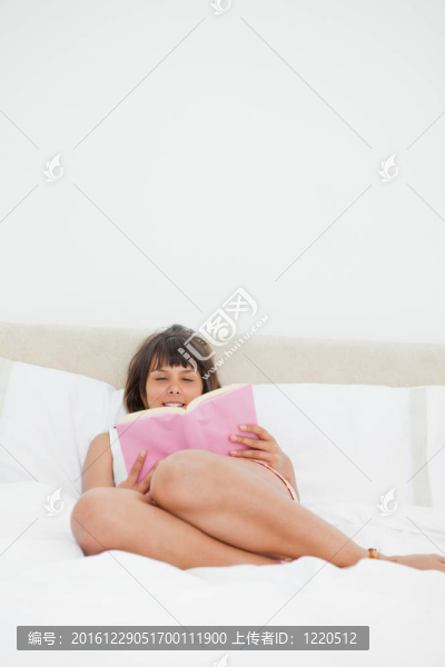 微笑的學(xué)生穿著凌亂的睡衣讀一本書