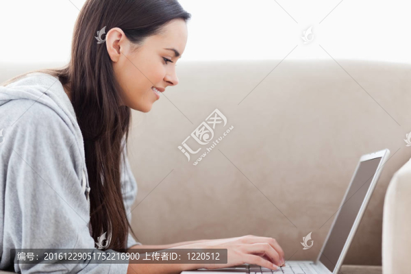 躺在沙發(fā)上的女人在筆記本電腦上打字