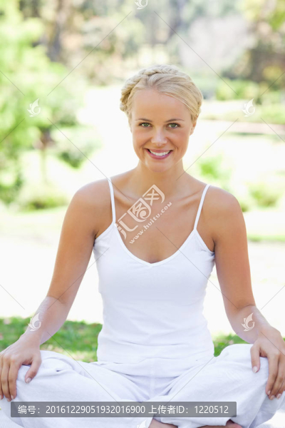 微笑的女人在草坪上的瑜伽姿勢(shì)