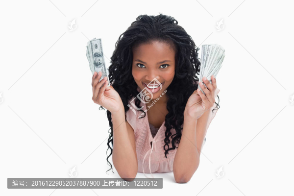 一個年輕的女人拿著美元在凸輪上微笑