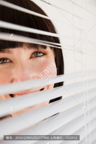 一個(gè)女人透過(guò)百葉窗輕輕打開(kāi)