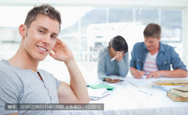 一個(gè)傻笑的學(xué)生坐在他的朋友面前他看起來(lái)