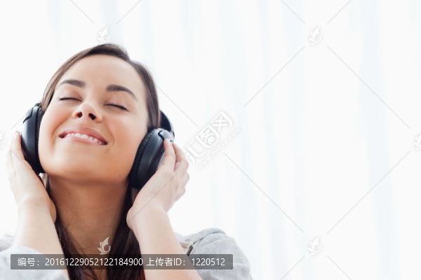 一個微笑的女人在聽她的耳機