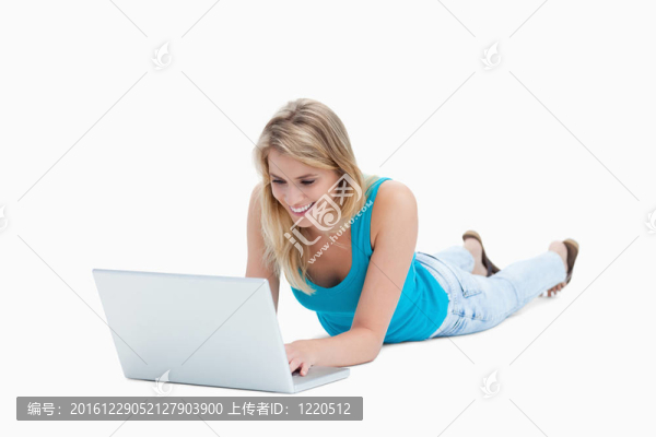 一個(gè)年輕女人躺在地板上，手里拿著一臺(tái)筆記本電腦