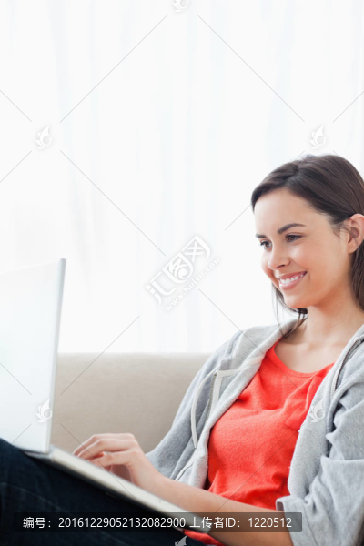 微笑的女人在沙發(fā)上使用筆記本電腦